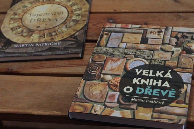 Dvě knihy na téma dřeva leží na dřevěném stole.