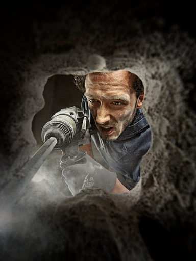 Muž vrtá do zdi vrtacím kladivem