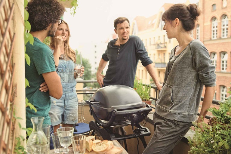 Skupina lidí griluje na balkoně s chlebem a nápoji