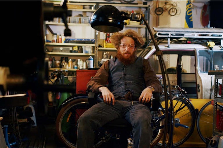 Dílna se osobou, jízdními koly a nářadím v pozadí