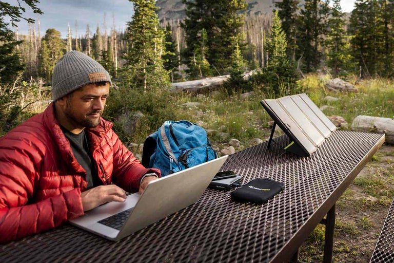 Muž používá notebook se solárním panelem na stole venku