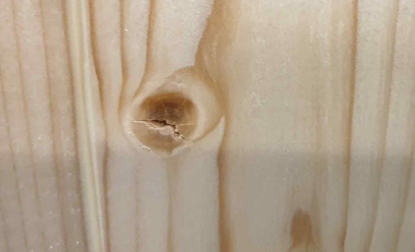 Detail dřevěného povrchu se sukem a kresbou