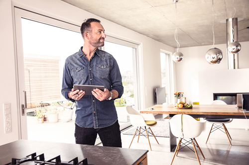 Muž s tabletem ve světlém obývacím pokoji s jídelním stolem a židlemi