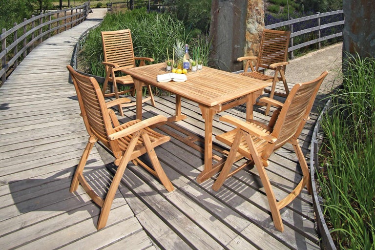 Zahradní scéna s dřevěným stolem a čtyřmi dřevěnými židlemi na dřevěné terase