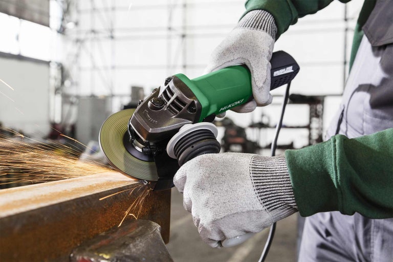 Osoba používá úhlovou brusku značky Hikoki k broušení kovu.