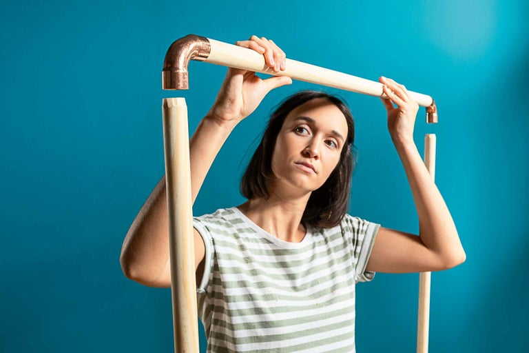 Žena montuje měděnou trubku s dřevěnou tyčí pro kutilský projekt