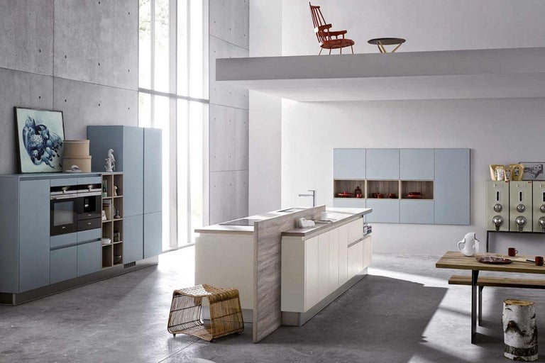 Světlá kuchyně s varným ostrovem, jídelním stolem a židlemi v moderním designu.