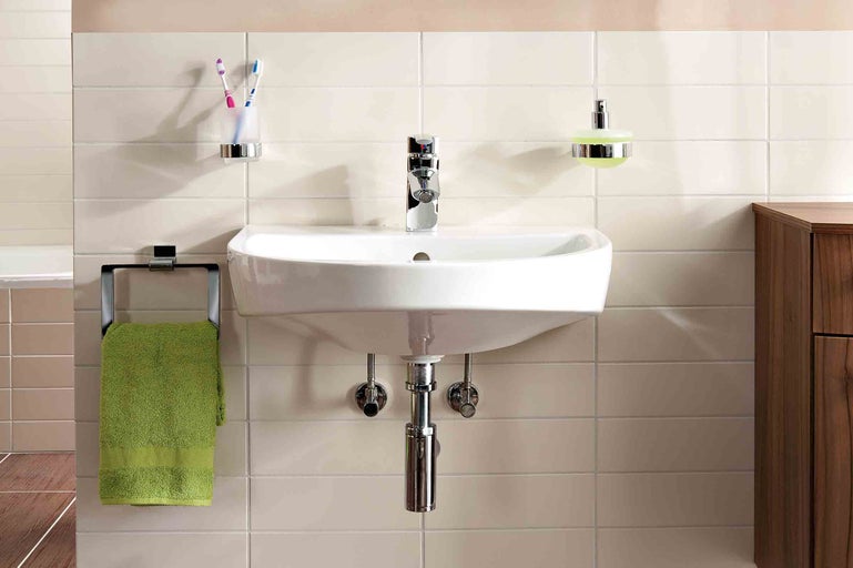 Koupelna s umyvadlem, baterií, držákem na ručníky, dávkovačem mýdla a kelímkem na zubní kartáčky