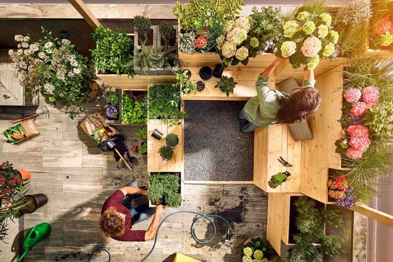 Pohled shora na městskou zahradu s rostlinami, zeminou a zahradnickým nářadím