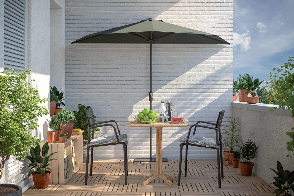 Balkon se zahradním stolem, židlemi a slunečníkem před cihlovou zdí