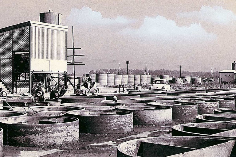 Průmyslový areál s betonovými nádržemi, budovami a vozidly
