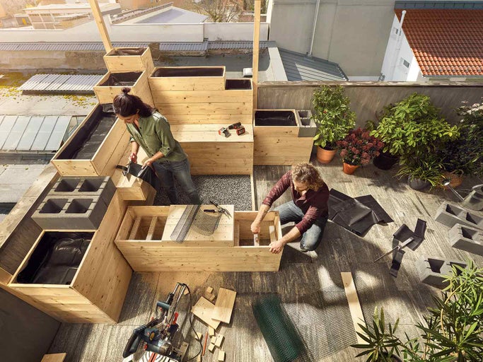 Střešní zahrada s vyvýšenými záhony ze dřeva a dvěma lidmi, kteří zahradničí