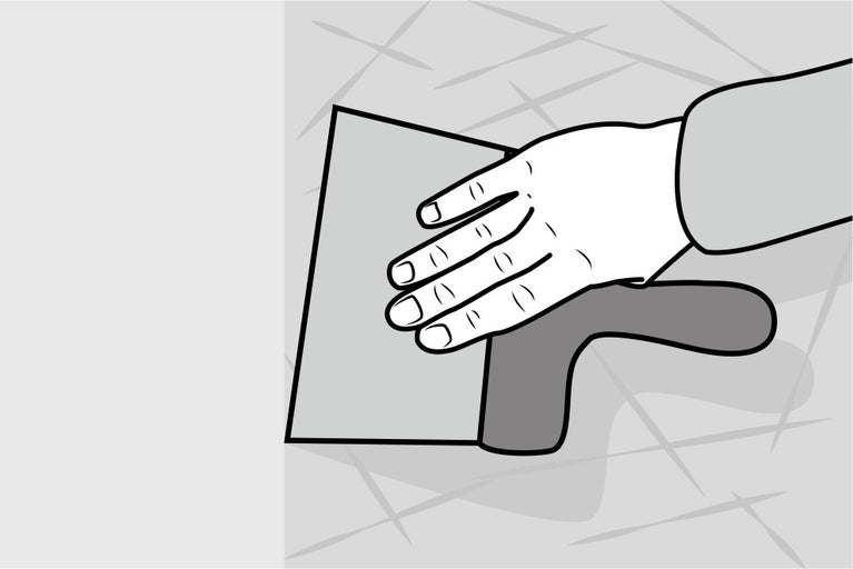 Ruka se špachtlí při spárování dlaždic