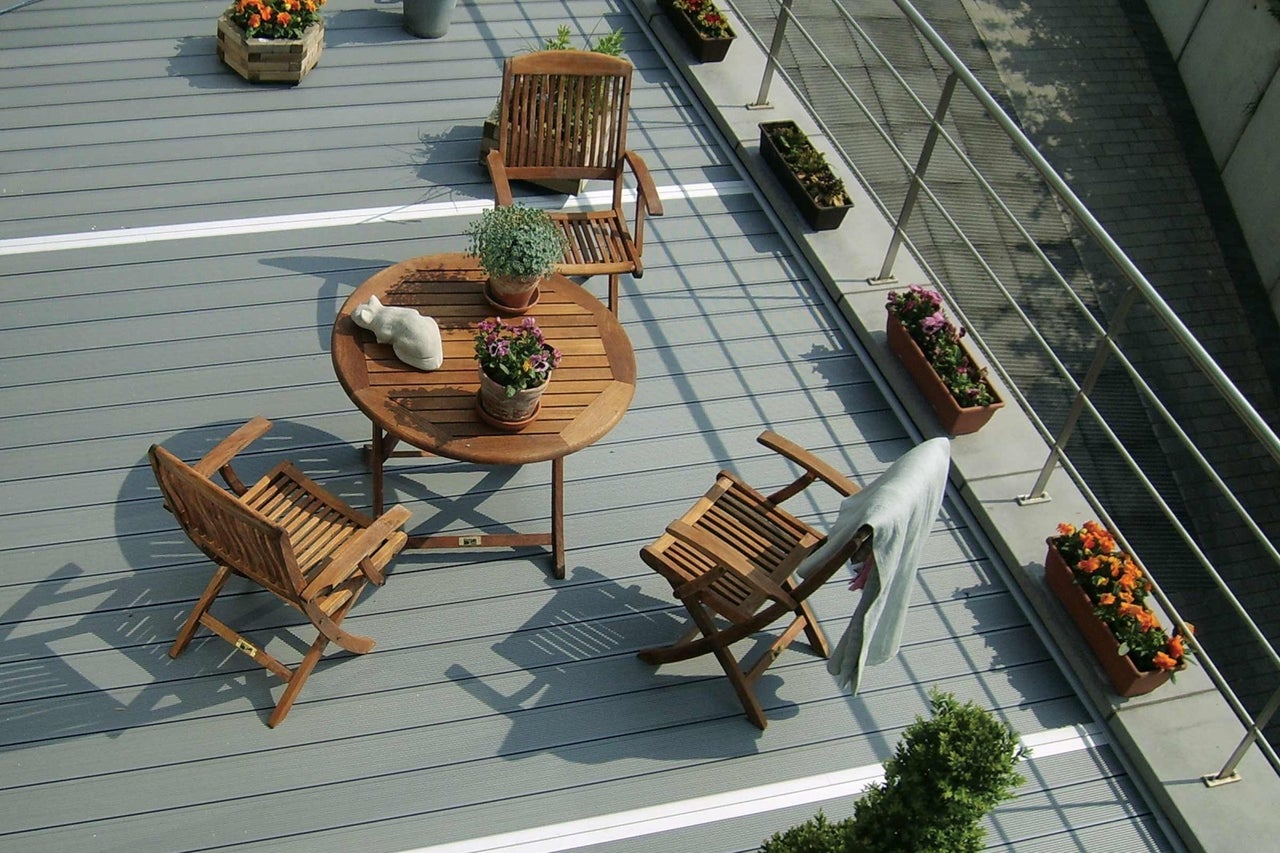 Balkon s dřevěnou podlahou, zahradní stůl a židle