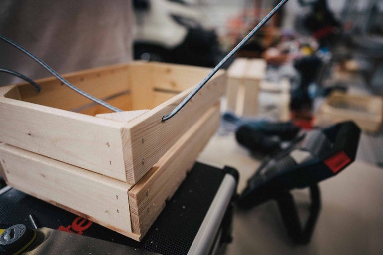 Dvě světlé dřevěné bedny naskládané s provazovými držadly