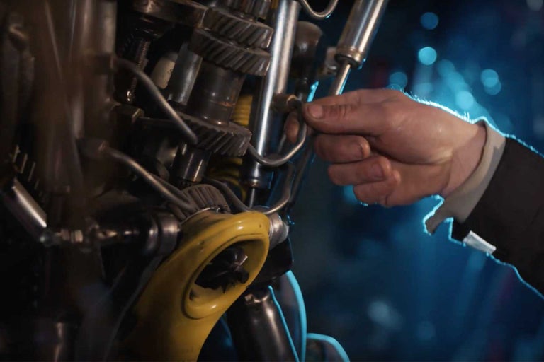 Detail ozubených kol a ruky utahující šroub