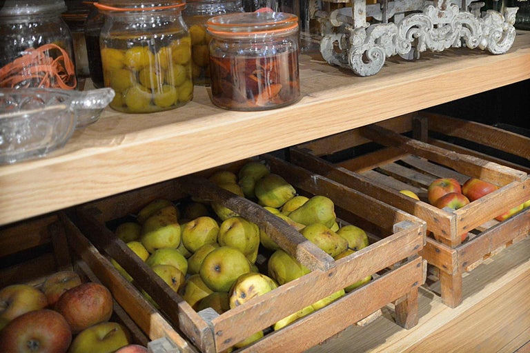 Dřevěná police s bednami ovoce a zavařovacími sklenicemi