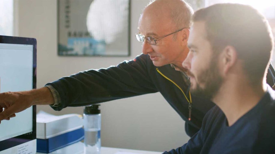 Dva lidé pracují společně na počítači