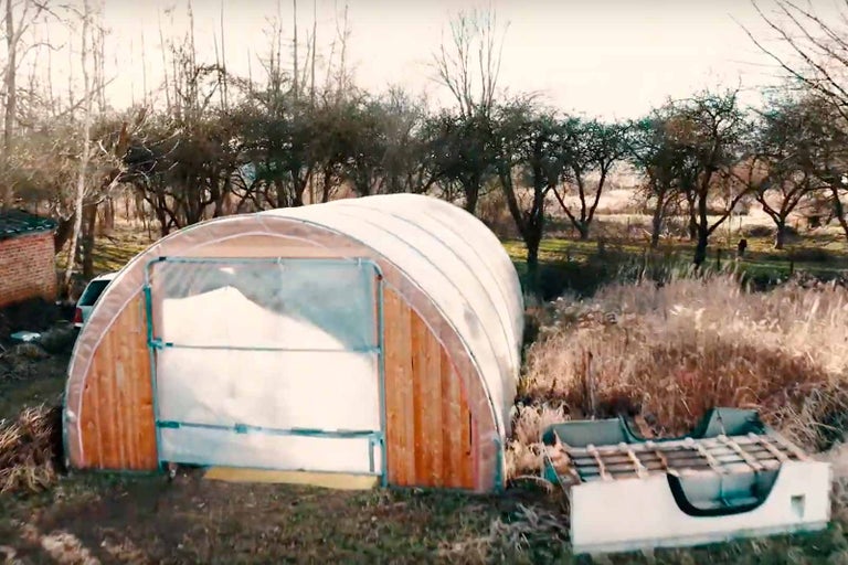 Skleník s dřevěným rámem a průhledným krytem na zahradě