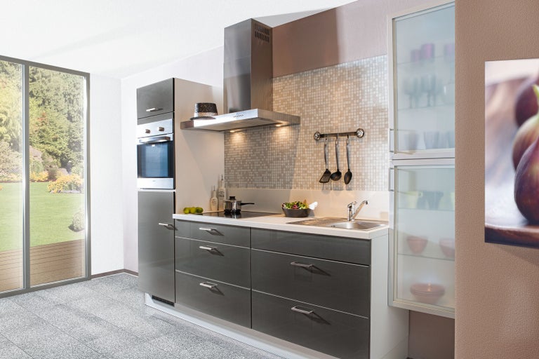 Světlá kuchyně s kuchyňskou linkou, digestoří, dřezem a velkým oknem s výhledem do zahrady