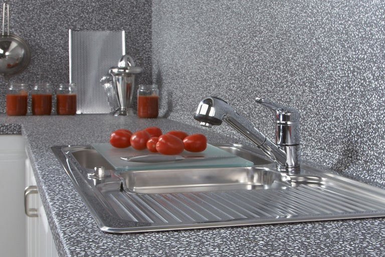 Kuchyňský dřez s rajčaty na prkénku a vodovodní baterií