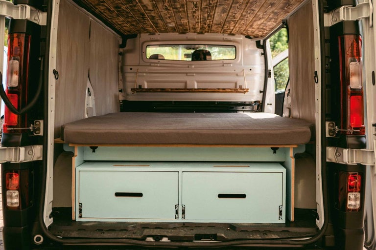 Interiér obytného vozu s postelí, zásuvkami a dřevěným stropem