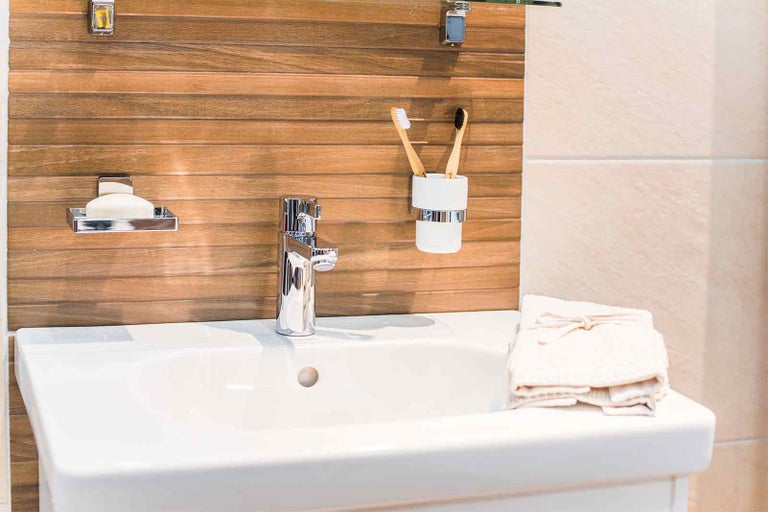 Umyvadlo s baterií, miska na mýdlo, kelímek na zubní kartáčky a ručníky v koupelně