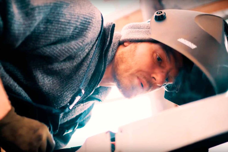 Muž se svářečskou kuklou při svařování