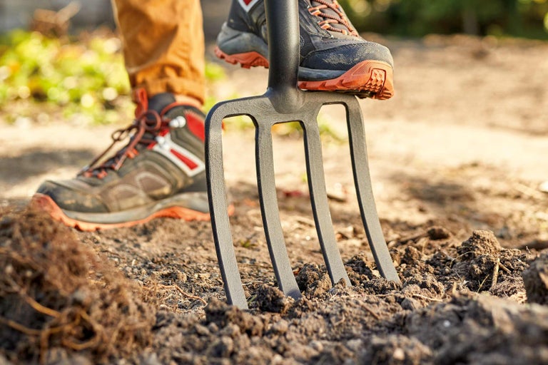 Detailní záběr rycích vidlí zatlačených botou do země