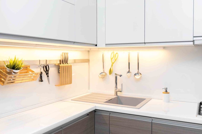 Kuchyňský dřez s kuchyňským náčiním, příslušenstvím a pracovní deskou v moderní kuchyni