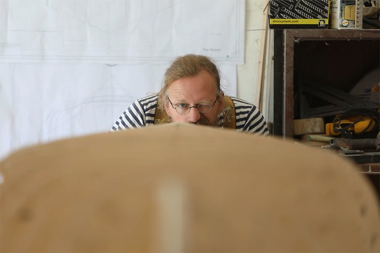 Muž s brýlemi pracuje se dřevem