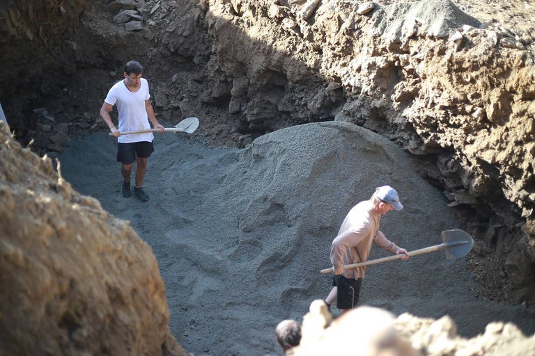 Dvě osoby pracují s lopatami ve výkopu.