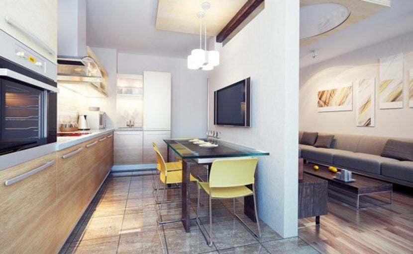 Světlá kuchyně a obývací pokoj s dřevěným kuchyňským nábytkem, skleněným jídelním stolem a televizí