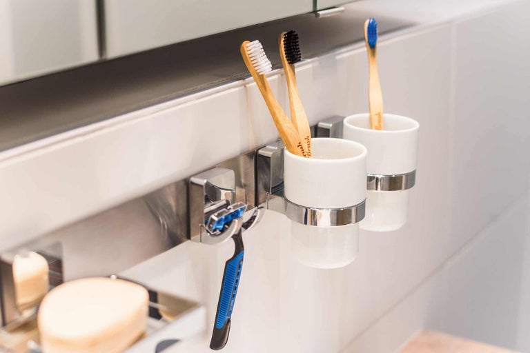 Scéna v koupelně se zubními kartáčky, kelímky na zubní kartáčky a holicím strojkem
