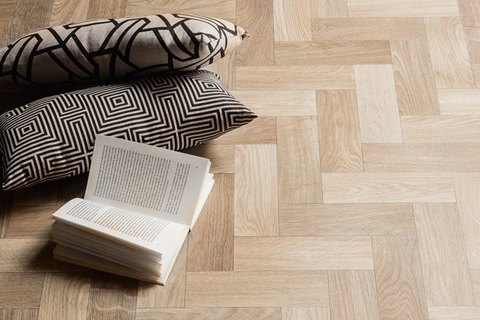 Podlahová krytina se vzorem rybí kosti, polštáře a kniha