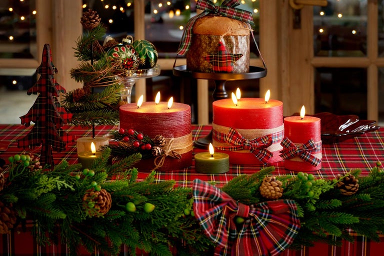 Slavnostně prostřený stůl s hořícími svíčkami, jedlovou zelení, dekoracemi a panettone