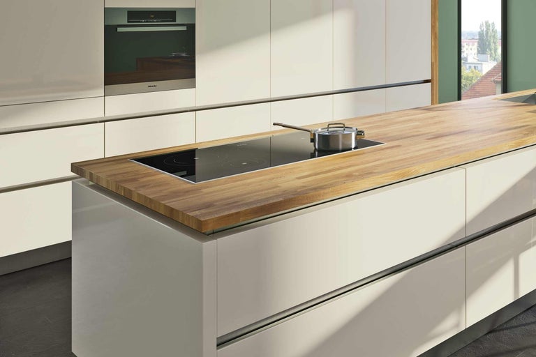 Kuchyňský ostrůvek s dřevěnou pracovní deskou, indukční varnou deskou a hrncem