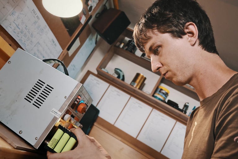 Osoba manipuluje s bateriemi v elektronickém zařízení.