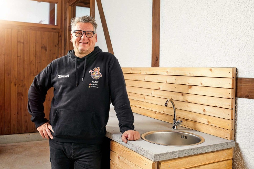 Venkovní kuchyně s dřezem a dřevěnou stěnou a osobou