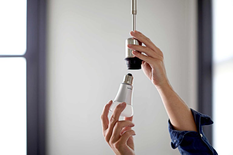 Osoba šroubuje žárovku do objímky.