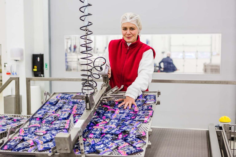 Žena balí produkty na montážní lince v továrně