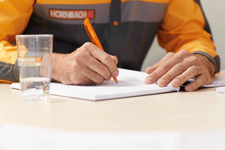 Zaměstnanec společnosti Hornbach píše do poznámkového bloku.