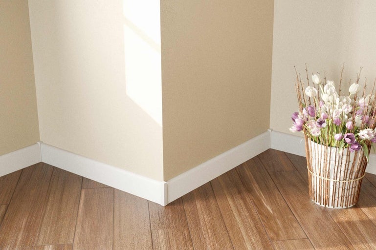 Pohled na stěnu s bílými podlahovými lištami a dřevěnou podlahou