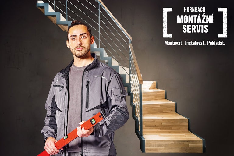 Řemeslník drží vodováhu před schodištěm, v pozadí montážní servis Hornbach