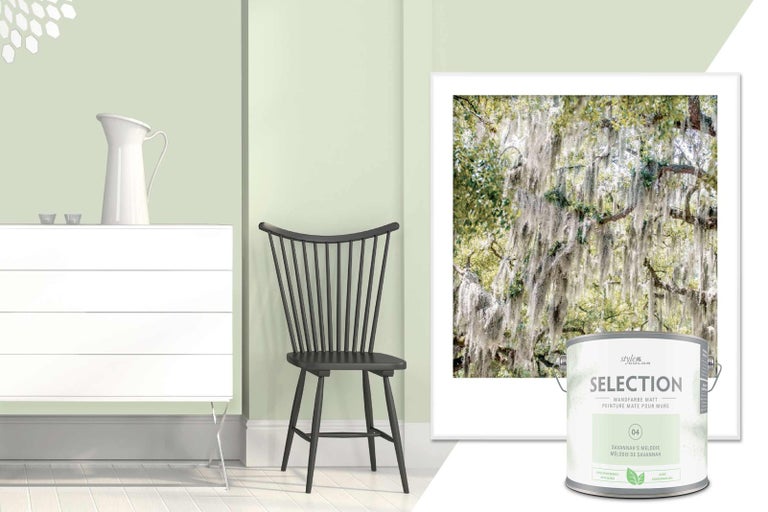 Světlý, přátelský interiér s barvou na stěny, komodou, židlí, obrazem a plechovkou barvy