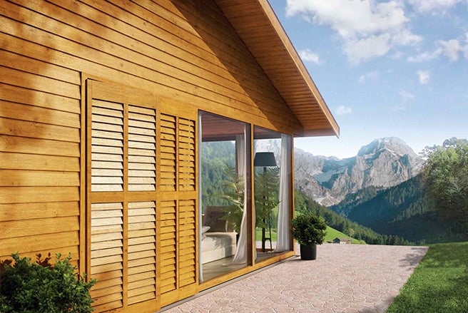 Dřevěný dům s okenicemi a výhledem na hory
