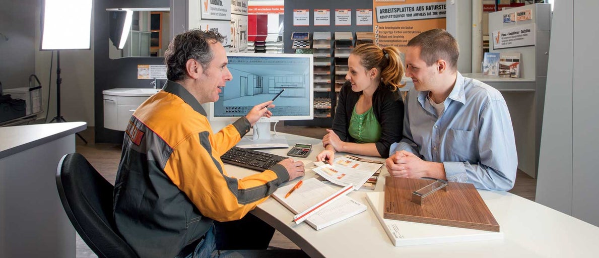 Zaměstnanec společnosti Hornbach radí zákazníkům s návrhem kuchyně na počítači.