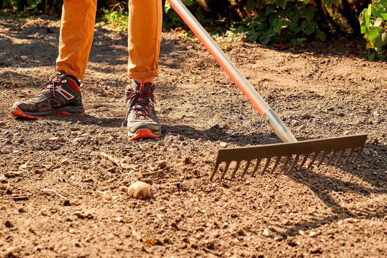 Osoba pracuje s hráběmi na zahradě
