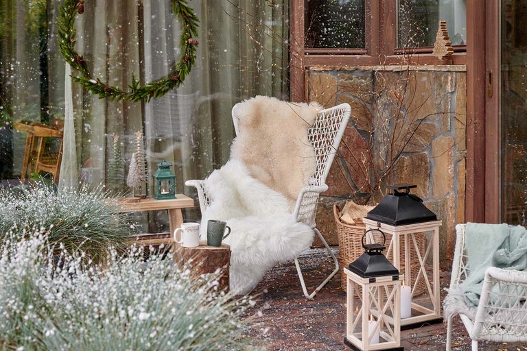 Zimní zahradní dekorace se židlí, lucernami a dekoracemi.
