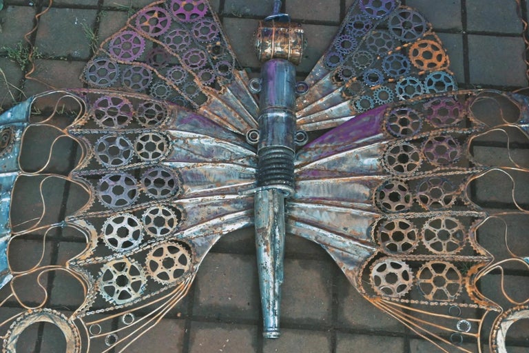 Dekorativní kovová socha motýla vyrobená z ozubených kol a řetězů
